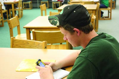 Staying in touch: Senior Austin Cunningham checks his cell phone in the media center during his AUT. Students may text in the media center, but not in classrooms without teacher permission.