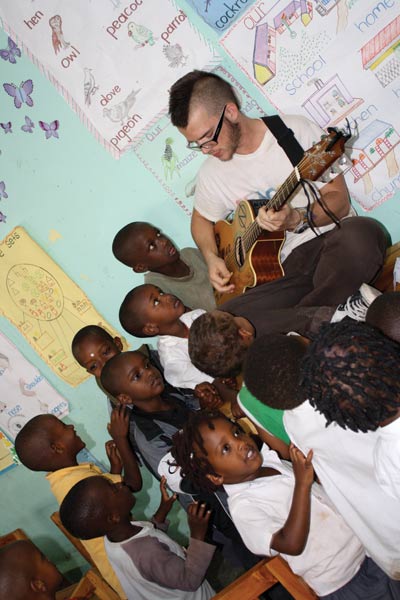 Singing for fun: RBHS alumnus Austin Kolb plays his guitar for young children in Rwanda. Photo provided by Austin Kolb.