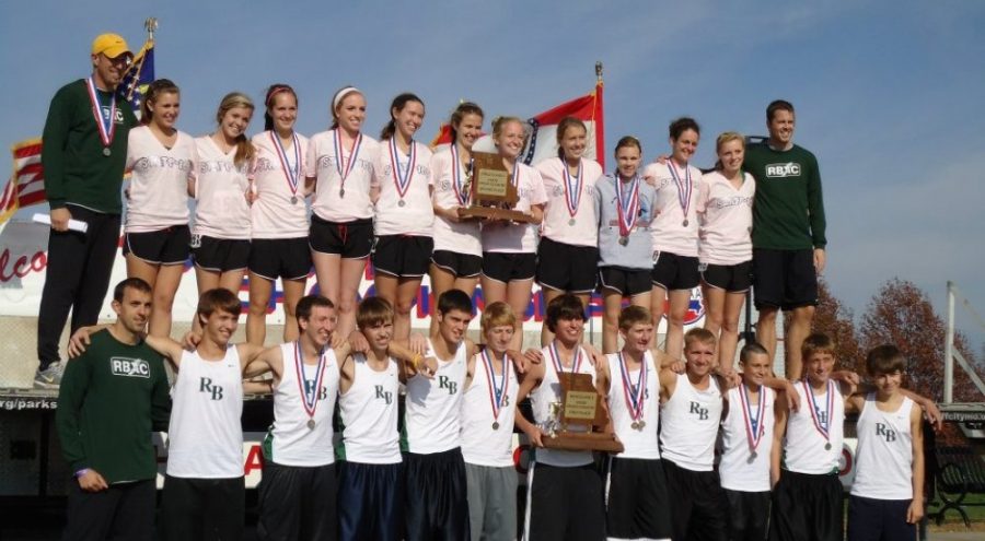 Both the boys and girls varsity cross country team pose for photos with their medals and trophies. Both teams broke school records at the state championship, with the boys raking in first place and the girls taking second.