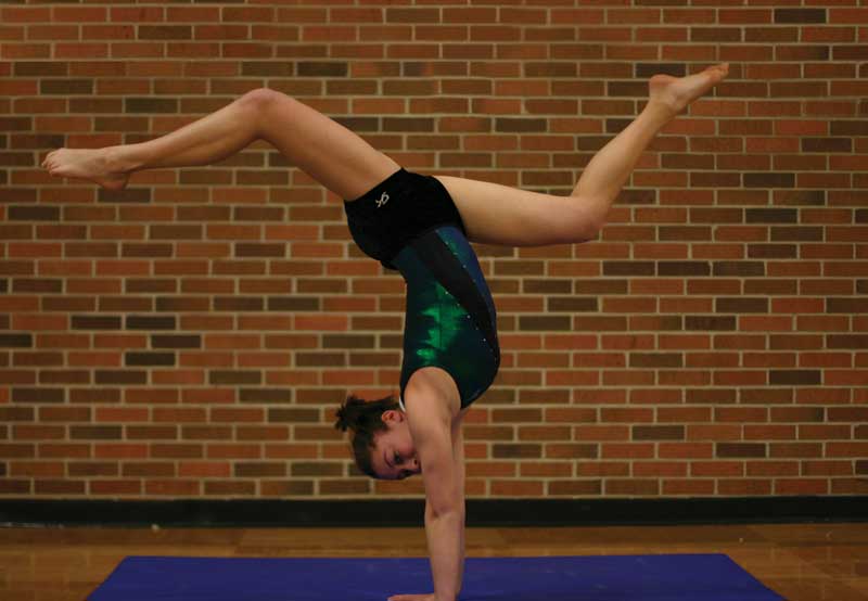 Incredibly flexible: Junior Angie Kern stretches before a gymnastics routine. A member of both varsity golf and gymnastics teams, Kern had to choose between one or the other. She has continued gymnastics to great success. Photo by Halley Hollis.