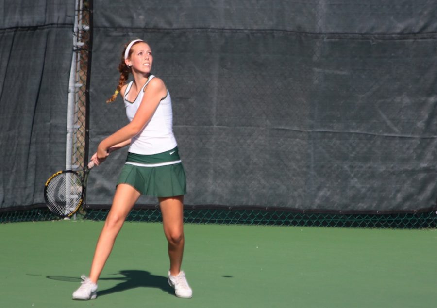 Senior Gracie Strawn prepares to return a high-flying shot, scoring her a point in her singles match. Photo by Asa Lory