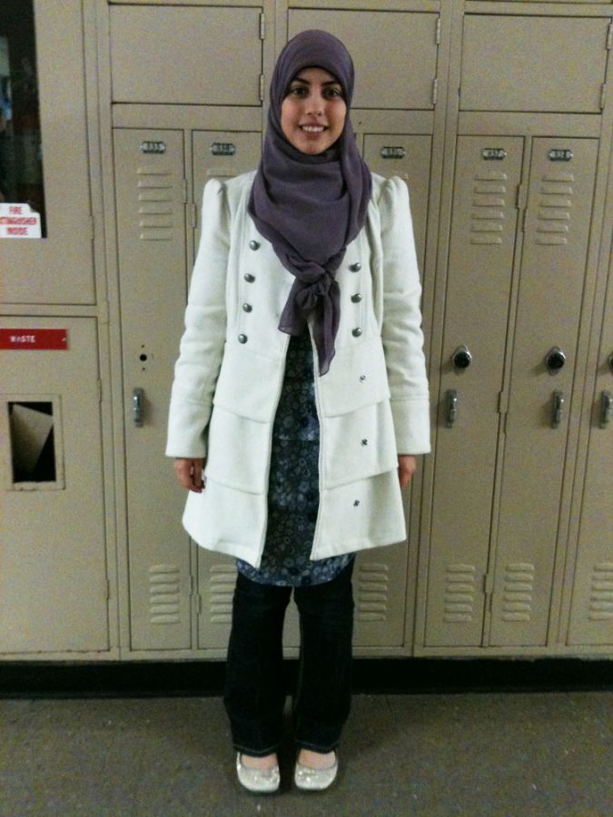Senior Duha Shebib sports a white pea coat with a purple hijab and floral shirt. Photo by Lauren Puckett