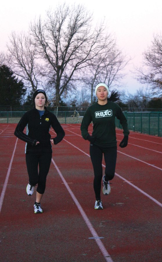 Senior+Jordyn+Kendall+and+junior+Joanna+Zhang+run+on+the+track+early+one+Saturday+morning+to+prepare+for+the+upcoming+heart+of+track+season.+Photo+by+Paige+Kiehl+