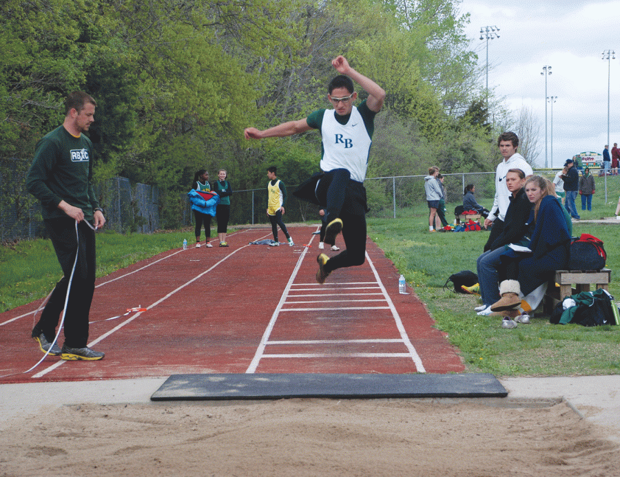 Long Jump: Junior Danny Lantz lauches into a sandpit in an attempt to hit a personal best in the long jump. Fellow teammates and Coach Sasser eagerly awaited Lantzs results. 