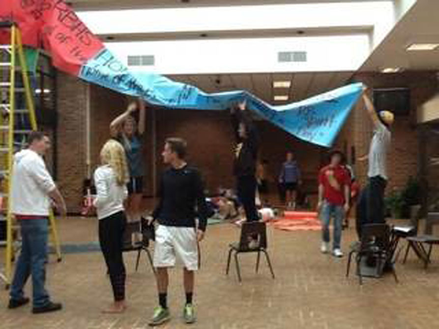Student council members hang the homecoming banner in the main commons on Monday September 20, 2013. 