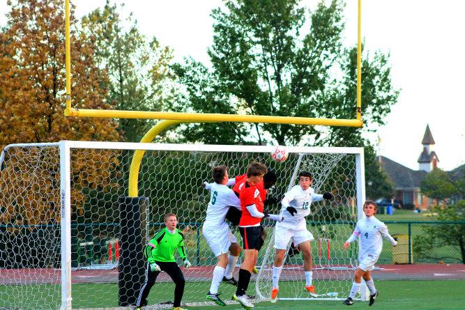 Jeff City kicks a corner kick and their players attempt a header, while number 12, Blake Hausman, grade 12, jumps to defend the goal.