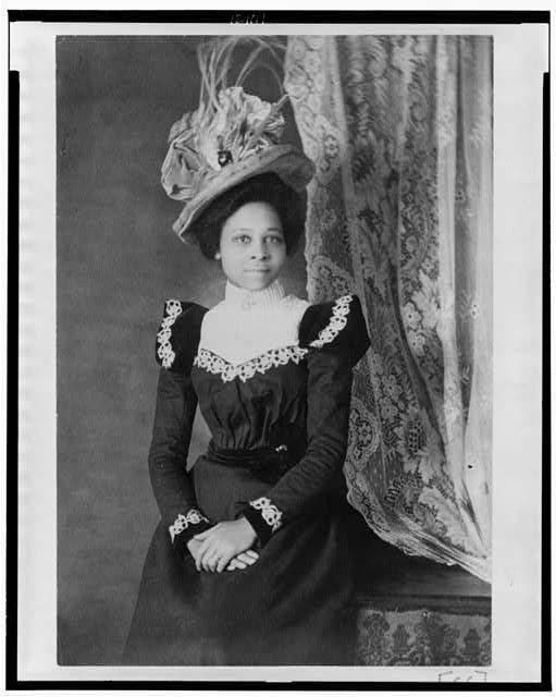 Young African American woman, three-quarter length portrait, facing slightly right, with hands folded on her lap. Collection: African American photographs for the Paris Exposition of 1900. Used with permission in fair use doctrine. Source: http://hdl.loc.gov/loc.pnp/cph.3c21111