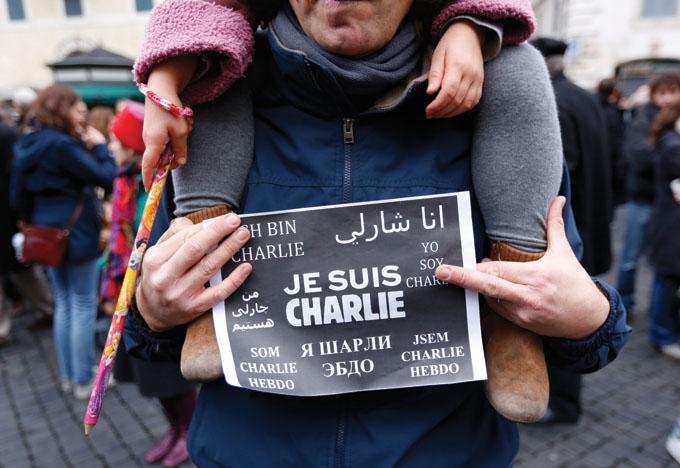 A man holds a sign  Je Suis Charlie (I am Charlie) signs as several hundred people gather in solidarity with victims of two terrorist attacks in Paris, one at the office of weekly newspaper Charlie Hebdo and another at a kosher market, in front of the French Embassy in Rome, Sunday, Jan. 11, 2015. (AP Photo/Riccardo De Luca)