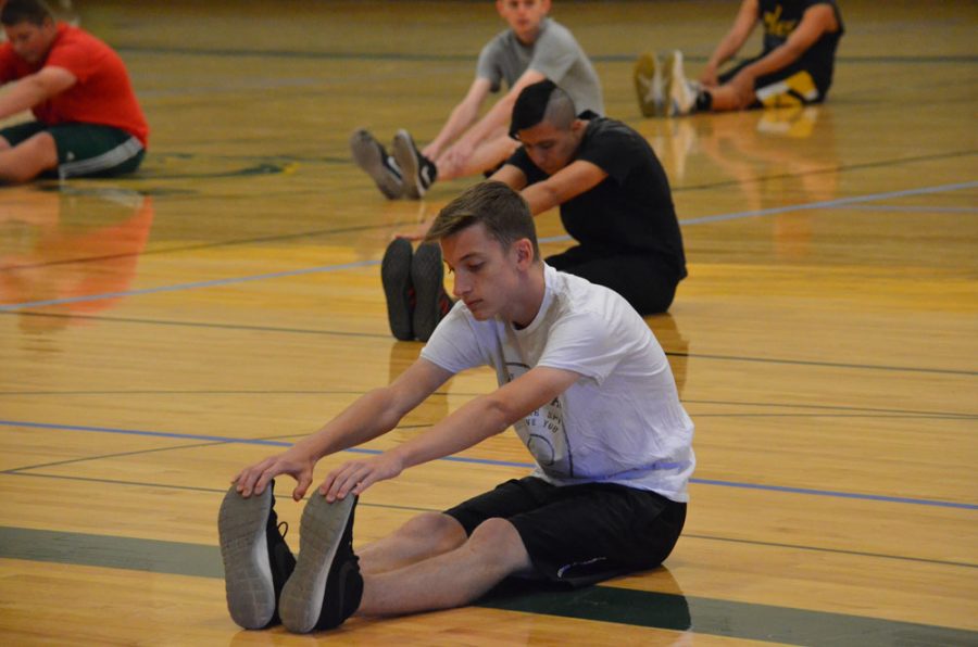 Junior Gabriel Fischer stretches at the beginning of Mens Team Sports with the rest of his classmates. Students are no longer required to change clothes before physical education courses, as long as they are already wearing appropriate athletic attire. photo by Caitlynn Nolte
