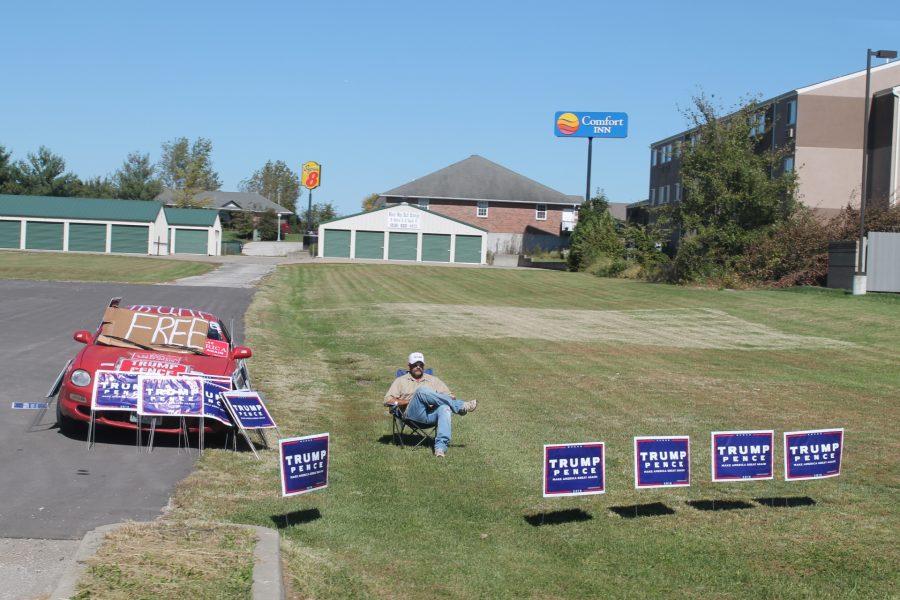 Man on the side of the road with Donald Trump endorsement posters on Oct. 8.