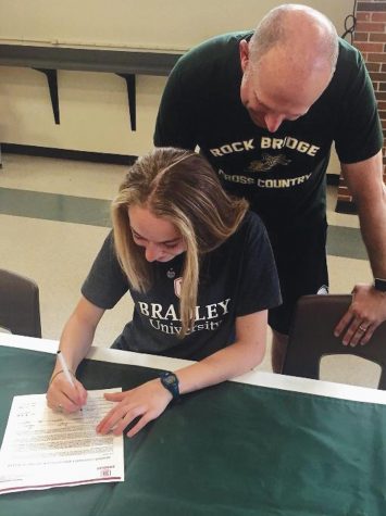 Letter of intent: Track and cross country coach Neal Blackburn
looks over his daughter, Aliyah Blackburn‘s shoulder,
who will run at Bradley University next year. Photo courtesy of Jamie Blackburn