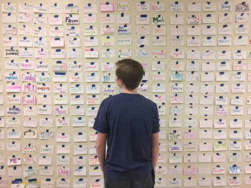 Sophomore Will Cover stands at the Wall of Happiness in the science wing. Photo by Jared Geyer