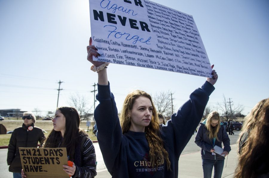 Senior+Olivia+Kady+holds+a+sign+with+the+names+of+victims+of+gun+violence.+It+reads+Never+again.+Never+forget.+Photo+by+Maya+Bell.