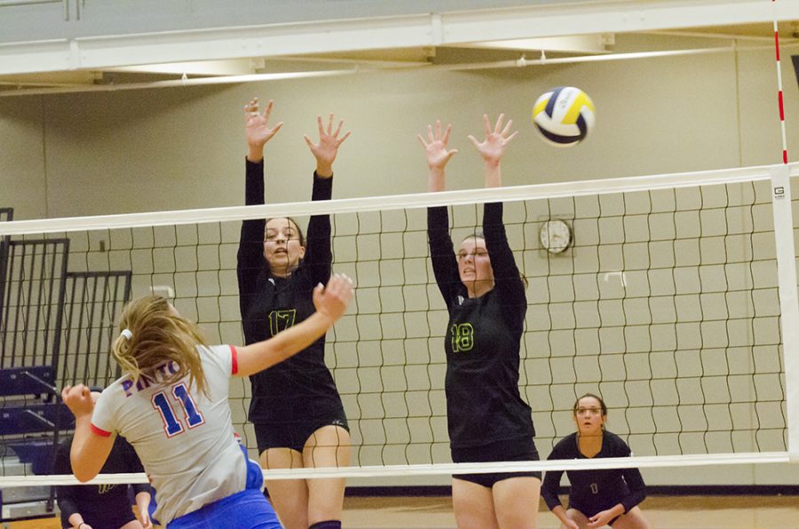 Junior Kennedy Robbins and sophomore Cassie Gray jump to block the ball during a match against California High School at the jamboree on August 23, while senior Kate Buster is poised to pass behind them.