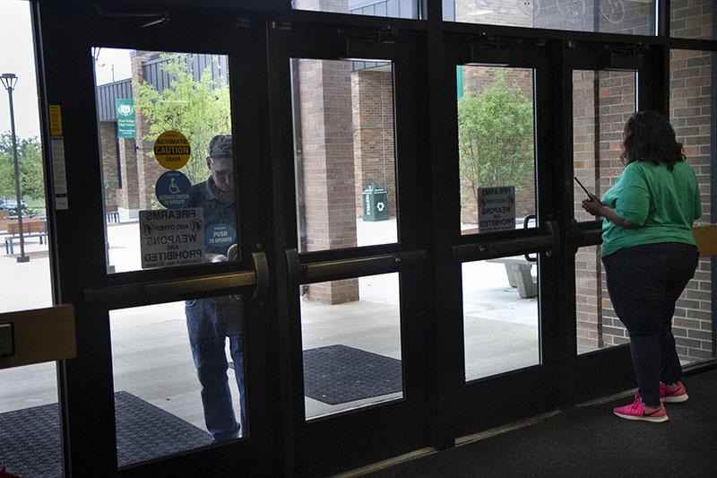 Custodial staff works with administrative staff to get the main commons doors to lock successfully during modified lockdown, Sept. 7. Photo by Camryn DeVore