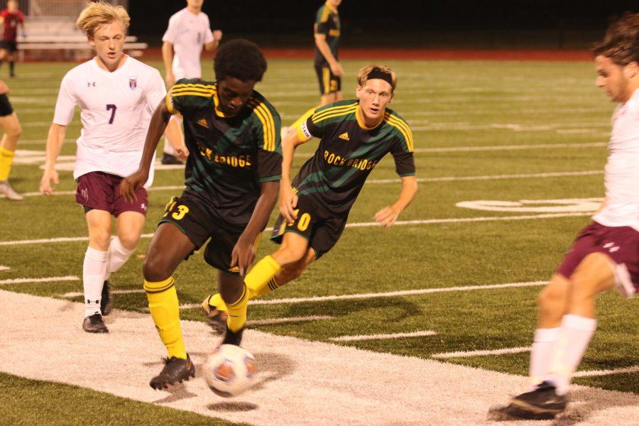 FOOTWORK: Senior Freddy Nene manages to control the ball as senior midfielder Jack Flink follows behind, as extra protection against De Smet. - Photo by George Frey.