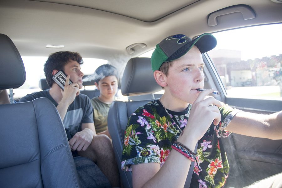 Cruising into the world of JUULing: (from left) Seniors Ben Yelton, Johnny Prado-Cox and Dylan Soper carpool to Hy-Vee at their lunch break Thursday, Sept 13. Yelton and Soper take hits from JUULs, the most popular brand of e-cigarettes. These resemble small USB drives. Photo by Maya Bell.
