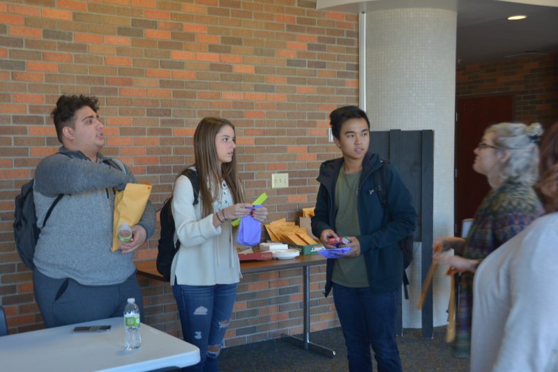 Compassion in Action club members juniors Zain Syed, Kate Bushnell and Toan Vu stand in the PAC loby with sponsor Lesley Thalhuber during A lunch on Nov. 13. Students in the club walked through the halls passing out small items, such as gum, hot chocolate or gloves, to peers and teachers.