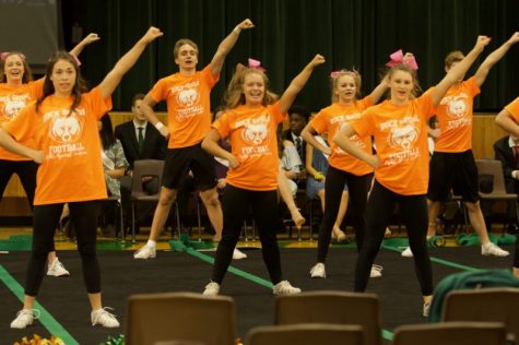Members of the cheerleading team perform a routine at the Homecoming assembly Oct. 12. The RBHS football team chose Leukemia as the cause for the 2018 game. The cheerleaders wore orange matching shirts in awareness. Photo by Grace Hervey.