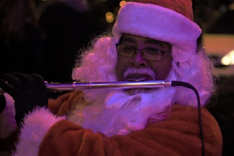 The flute playing Santa, aka Lamar Roberts, plays his flute under the magic tree to an adoring crowd. Photo by George Frey / Bearing News 