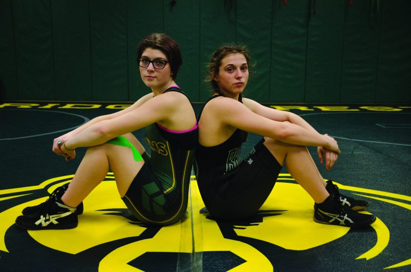 Junior Paige Hensley (left) and freshman Anna Stephens  pose before the Troy/Francis Howell North match Dec. 6. They are the only girls who wrestle for the Bruins. Photo by Allie Pigg.