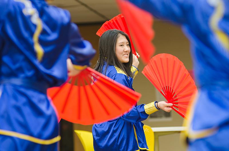 Sophomore Genney Zheng smiles joyfully while participating in a traditional Chinese dance that took place during the eighth grade visit to RBHS Friday, Jan. 25. The group consists of students in various levels of Chinese classes. Students often practiced in the east atrium during class time in anticipation for their performance for Global Village happening today.  Photo by Allie Pigg