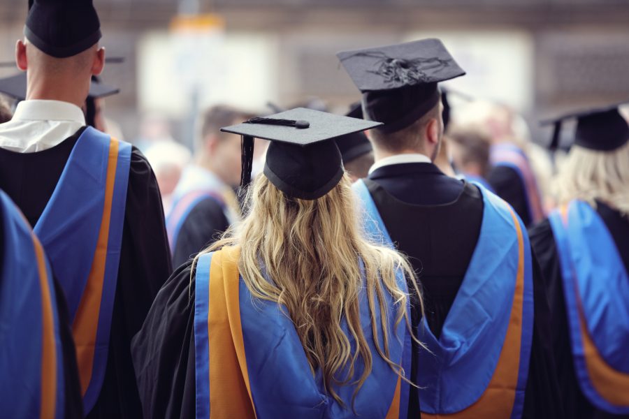 Graduates at university graduation  ceremony wearing mortarboard and gown