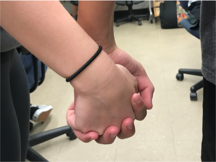 Couple holds hands while in class.