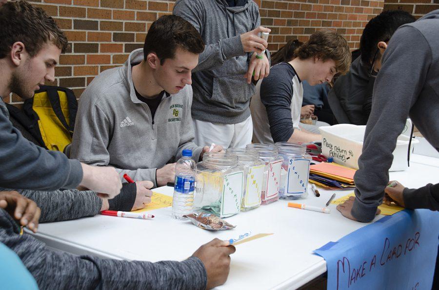 Senior Jacob Ungles and Cooper Deneke sit at a table in the Main Commons to write thank you cards to veterans on Friday, Nov. 22. Photo by Sarah Mosteller