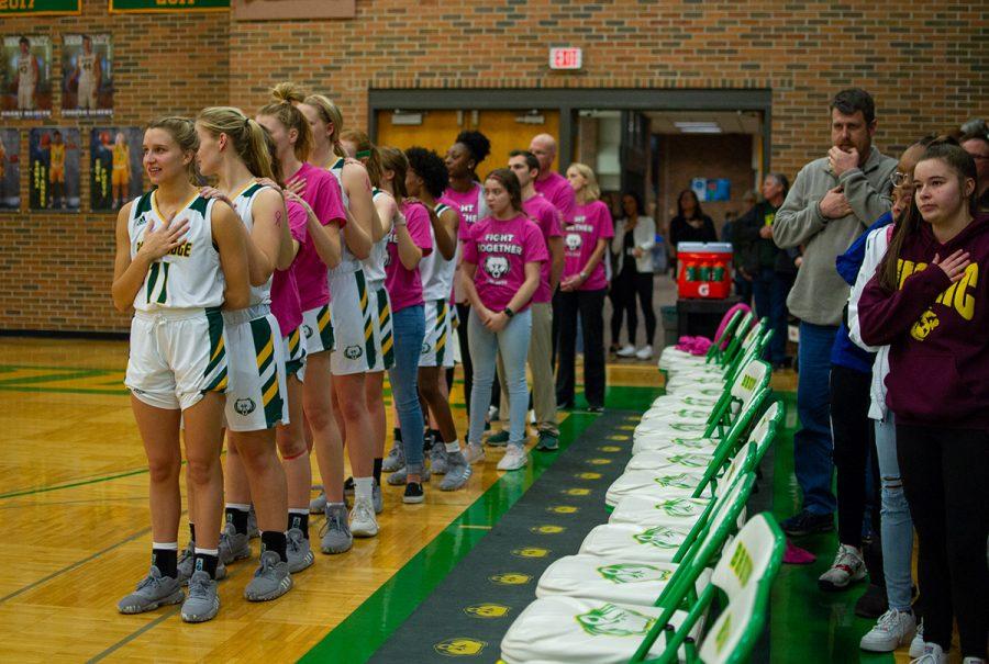 The varsity girls basketball game stands for the national anthem at their pink-out game Wednesday, Feb. 19. Following the national anthem, the announcer asked those who had either had cancer to were currently battling cancer to continue to stand. Photo by Ana Manzano.
