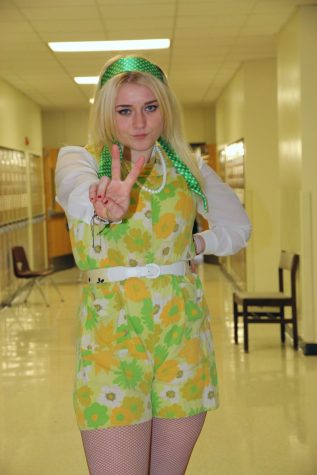 Junior Nora Croom pouts and holds a peace sign on her way to class 3rd hour. Her flower-child 60s inspired outfit comes from the theater costume closet, as she is close with the costumer of the choir program. 