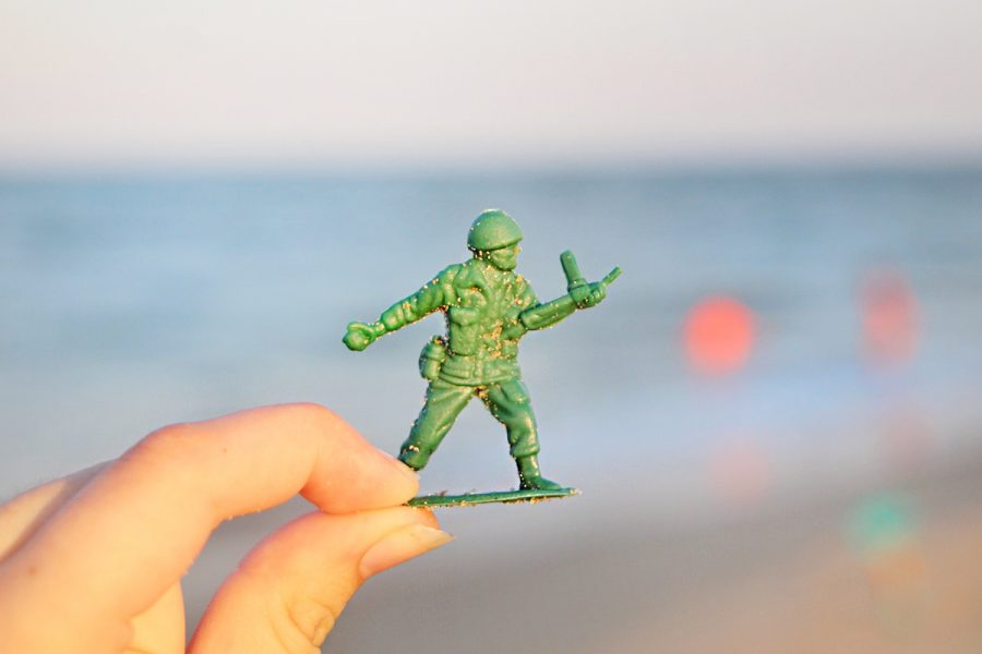 A green plastic toy soldier covered in sand was lifted from the Delaware shoreline. Abandoned toys still have a telling past. Photo by Sarah Mosteller.