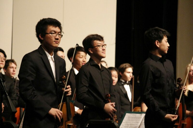 Sophomore Zihao Zhou (left) and senior Eric Kwon (right) stand for applause at the end of the orchestra concert. Photo by Jadyn Lisenby.