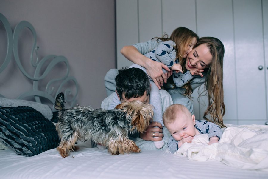 Portrait of happy young family playing on bed in the bedroom
