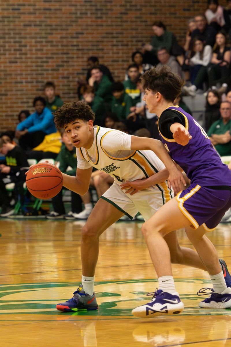 Eli Jones (12) dribbles the ball at the varsity boys' basketball game Feb. 17.