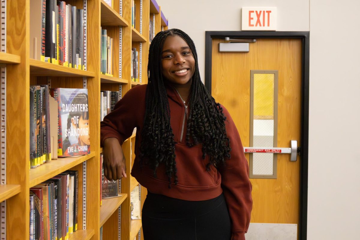 Simone Walker (11) poses against the shelves in the RBHS Media Center.